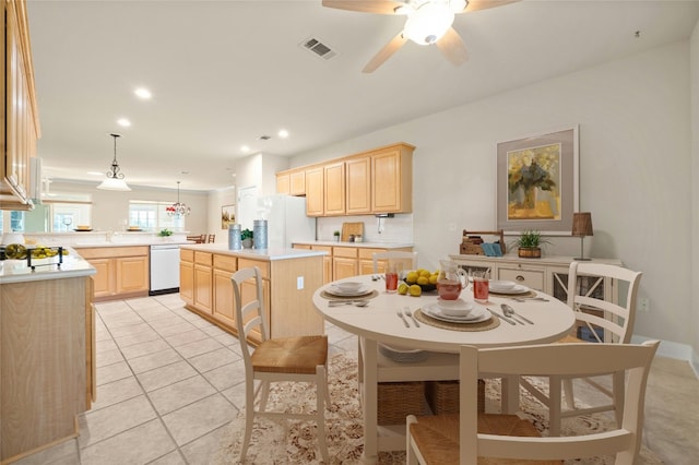 kitchen with light tile patterned flooring, white appliances, light brown cabinetry, decorative light fixtures, and a kitchen island