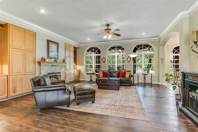 living room with ornamental molding, ceiling fan, a fireplace, and dark hardwood / wood-style flooring