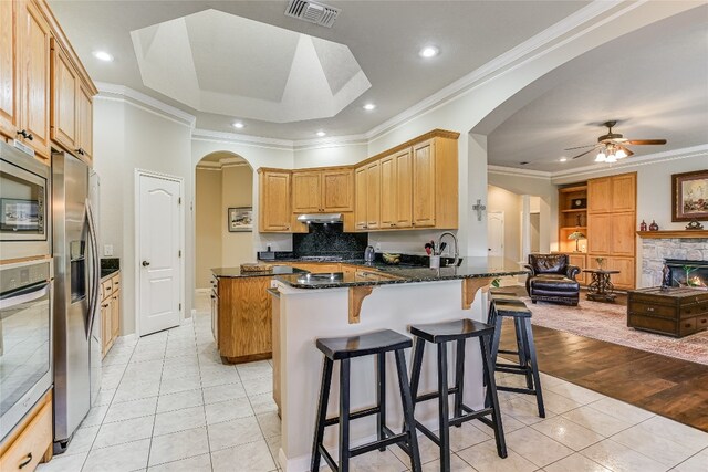 kitchen featuring dark stone counters, kitchen peninsula, light hardwood / wood-style flooring, ornamental molding, and ceiling fan