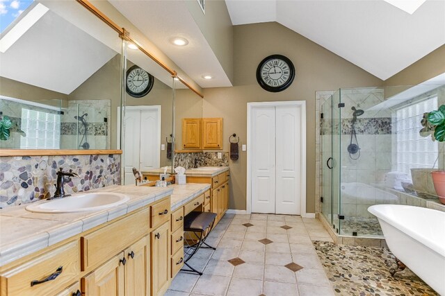 bathroom with a skylight, vanity, separate shower and tub, and high vaulted ceiling