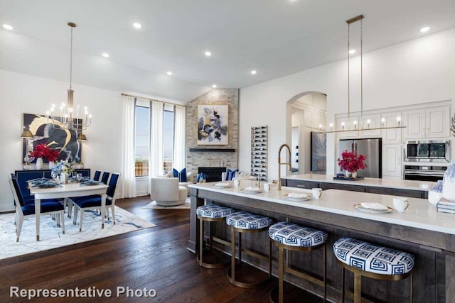 kitchen with pendant lighting, dark wood-type flooring, stainless steel appliances, a breakfast bar area, and a fireplace