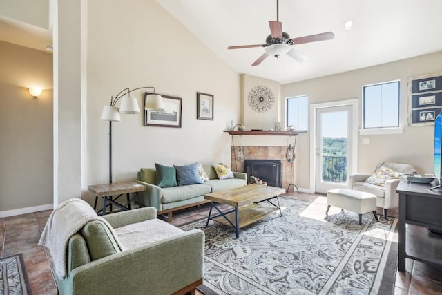 living room with ceiling fan, lofted ceiling, and a tile fireplace