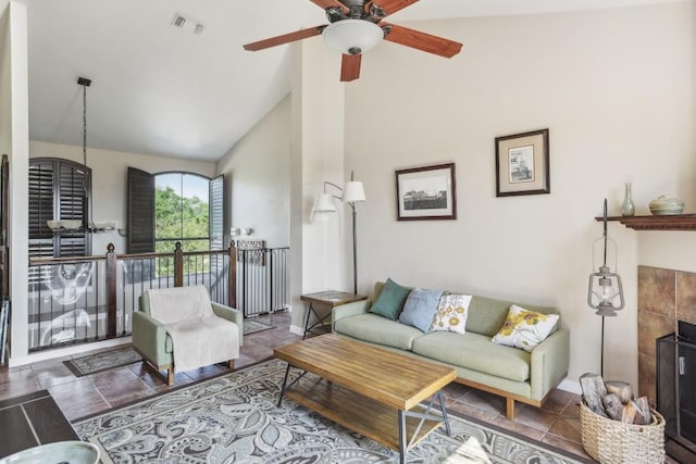 living room featuring ceiling fan, a tiled fireplace, and vaulted ceiling