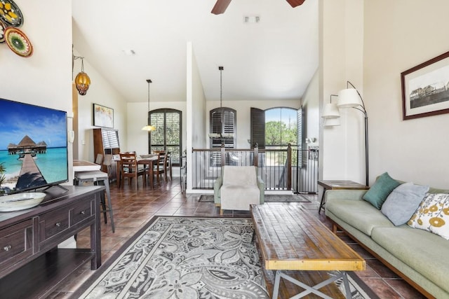 tiled living room with ceiling fan and high vaulted ceiling