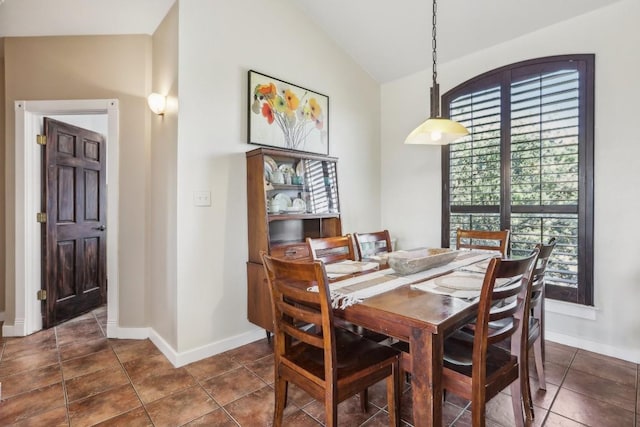 tiled dining room featuring vaulted ceiling