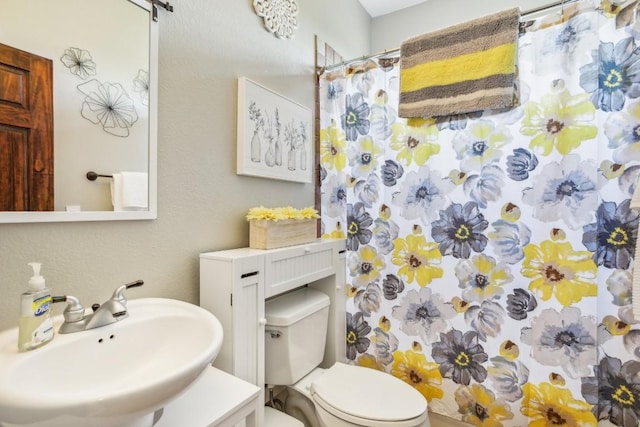 bathroom featuring toilet, sink, and walk in shower