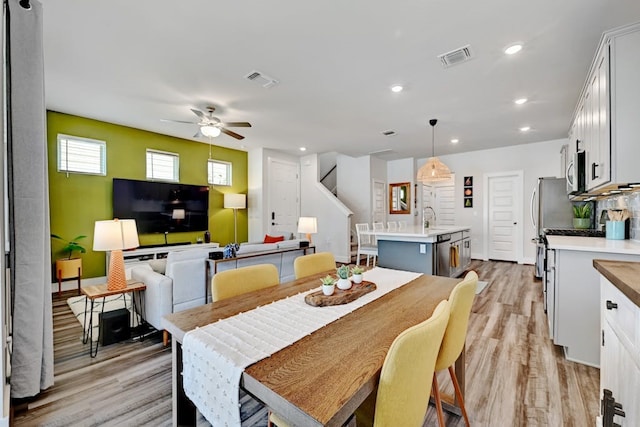 dining room with ceiling fan, light hardwood / wood-style flooring, and sink