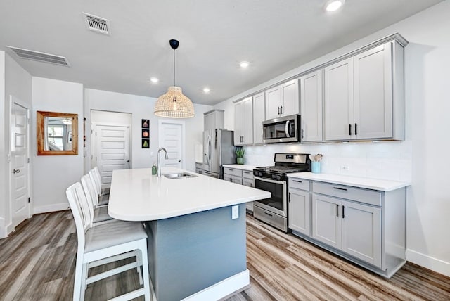 kitchen featuring stainless steel appliances, sink, tasteful backsplash, a breakfast bar, and gray cabinetry