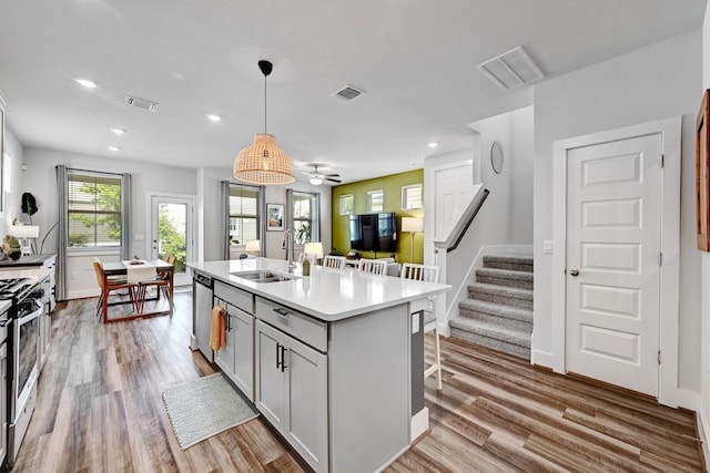 kitchen featuring sink, stainless steel appliances, ceiling fan, a center island with sink, and pendant lighting