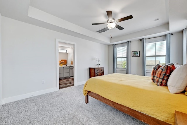 carpeted bedroom featuring ceiling fan, connected bathroom, and a tray ceiling