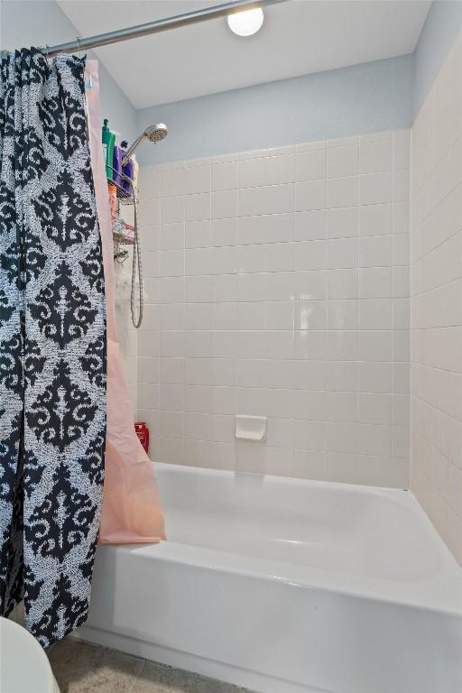 bathroom with shower / tub combo with curtain and tile patterned floors