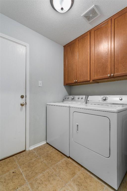 laundry room with cabinets, washing machine and clothes dryer, and a textured ceiling