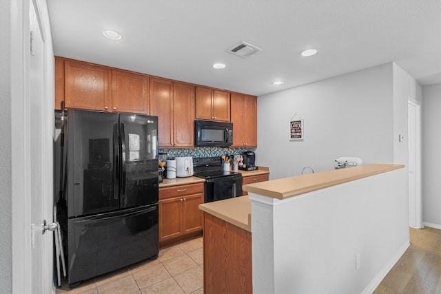 kitchen with decorative backsplash, light tile patterned floors, a kitchen island, and black appliances