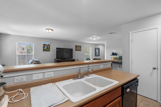 kitchen featuring dishwasher, sink, and light tile patterned flooring