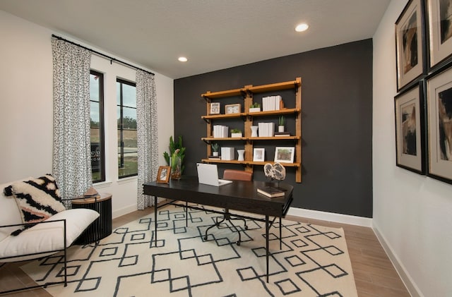 office space featuring light wood-type flooring and a textured ceiling