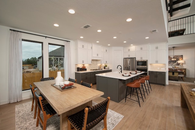 dining area featuring sink, light hardwood / wood-style floors, and a textured ceiling