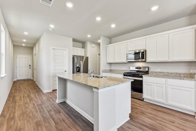239 Spirit St, Elgin, TX 78621 - kitchen with appliances with stainless steel finishes, a sink, wood finished floors, white cabinetry, and recessed lighting