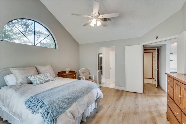 bedroom with ceiling fan, lofted ceiling, connected bathroom, and light hardwood / wood-style flooring