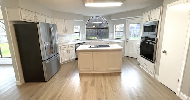 kitchen featuring tasteful backsplash, light wood finished floors, a center island, light countertops, and stainless steel appliances