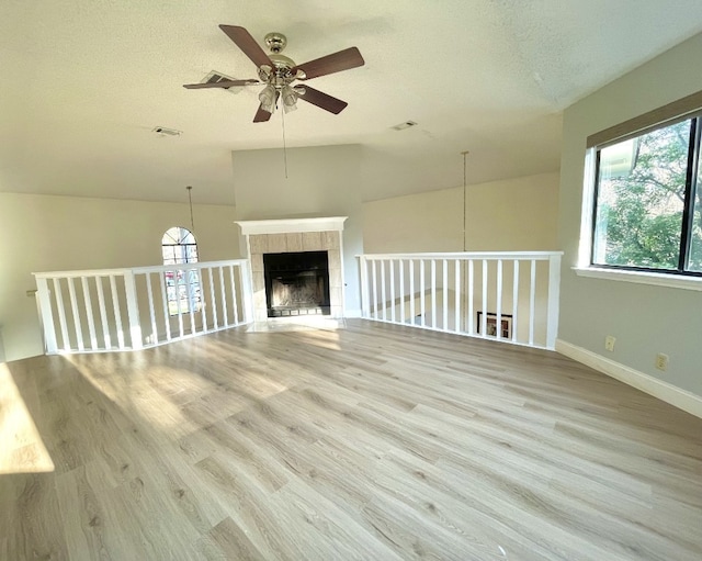 unfurnished living room featuring ceiling fan, a tile fireplace, a wealth of natural light, and lofted ceiling