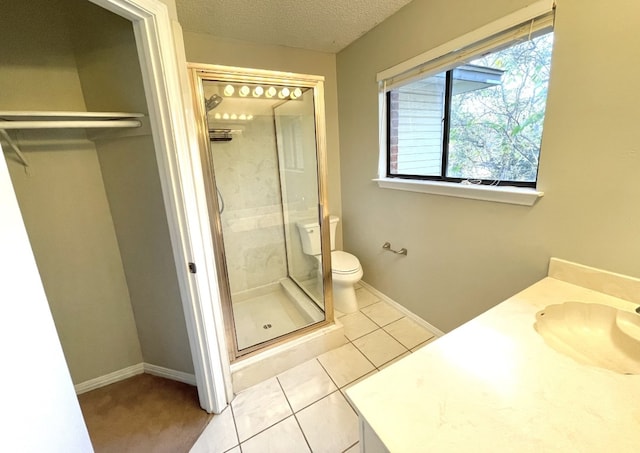 bathroom with toilet, a stall shower, a sink, a textured ceiling, and tile patterned flooring