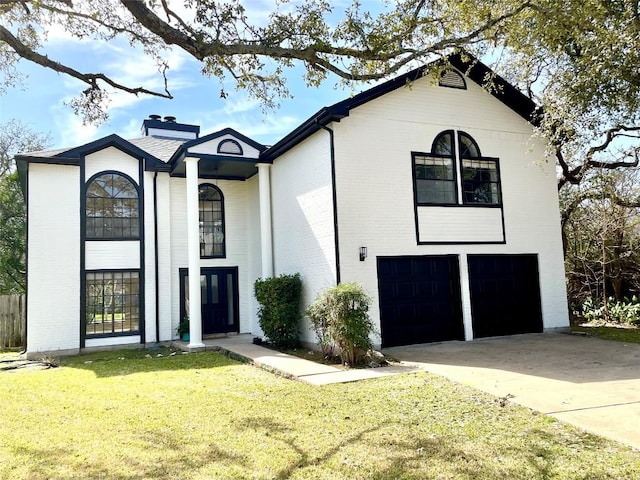 view of front of property with a front yard, driveway, an attached garage, a chimney, and brick siding