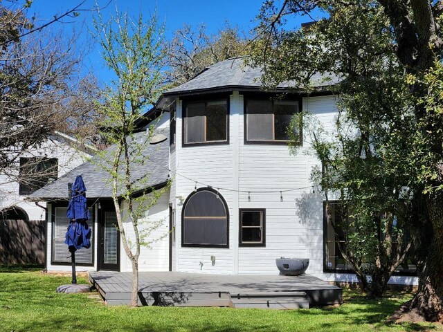 back of house featuring a deck, a lawn, fence, and roof with shingles