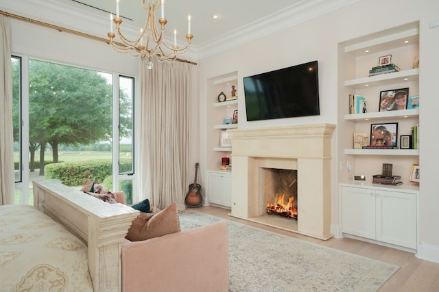 living room featuring built in shelves, a notable chandelier, light hardwood / wood-style flooring, and ornamental molding