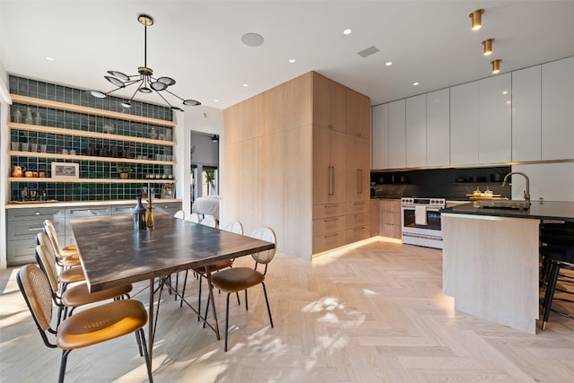 dining space with an inviting chandelier, light parquet floors, and sink