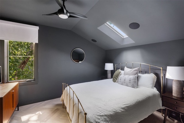 bedroom featuring ceiling fan, vaulted ceiling with skylight, and light parquet floors