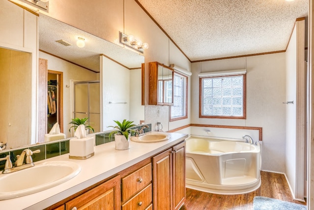 bathroom with vanity, lofted ceiling, wood-type flooring, independent shower and bath, and a textured ceiling