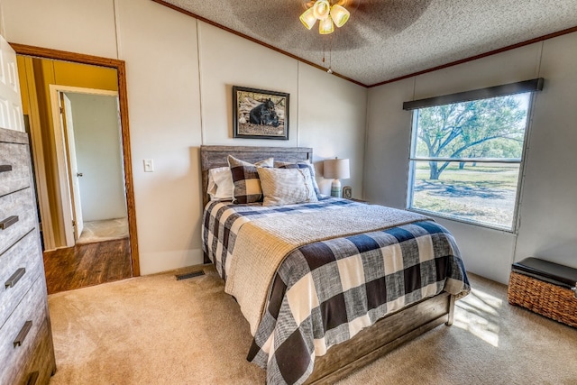 carpeted bedroom featuring a textured ceiling, crown molding, vaulted ceiling, and ceiling fan