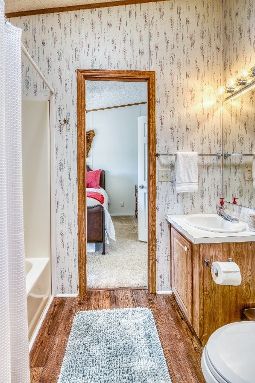 full bathroom featuring shower / bath combination with curtain, hardwood / wood-style flooring, vanity, and toilet