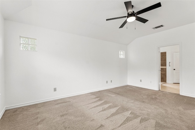 empty room featuring light carpet, vaulted ceiling, and ceiling fan