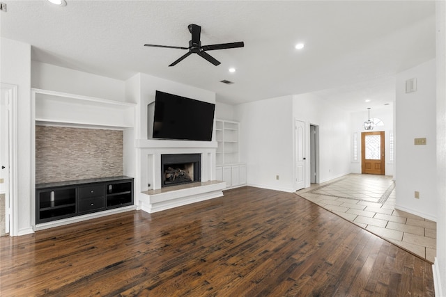 unfurnished living room featuring a textured ceiling, dark hardwood / wood-style flooring, built in features, and ceiling fan