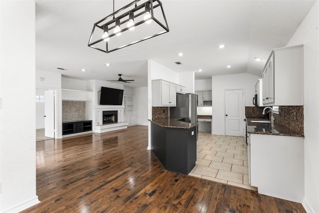 kitchen with ceiling fan, stainless steel refrigerator, backsplash, and dark wood-type flooring