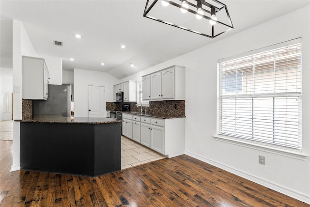 kitchen with light hardwood / wood-style flooring, lofted ceiling, appliances with stainless steel finishes, and tasteful backsplash