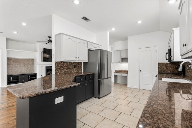 kitchen with ceiling fan, stainless steel fridge, sink, kitchen peninsula, and white cabinetry