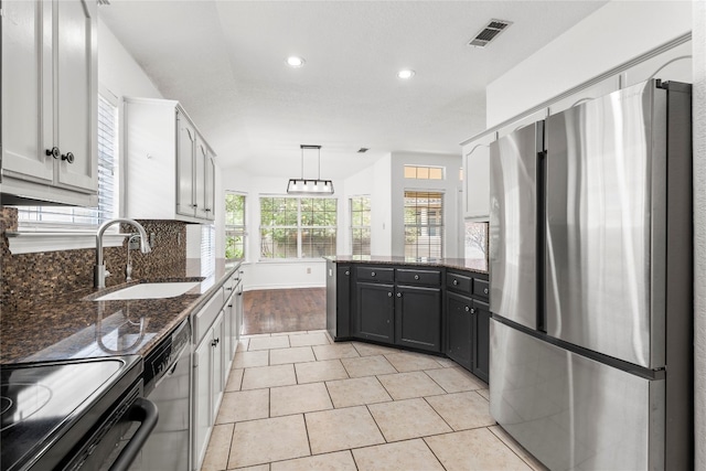 kitchen featuring hanging light fixtures, sink, white cabinetry, stainless steel appliances, and decorative backsplash