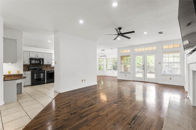 unfurnished living room featuring ceiling fan, a textured ceiling, and light wood-type flooring