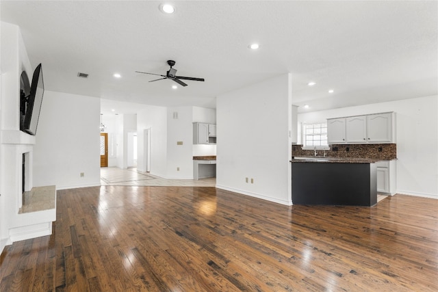 unfurnished living room featuring ceiling fan, sink, and dark hardwood / wood-style flooring