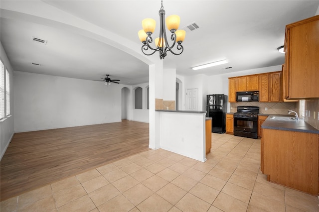 kitchen with hanging light fixtures, light hardwood / wood-style flooring, backsplash, black appliances, and ceiling fan with notable chandelier