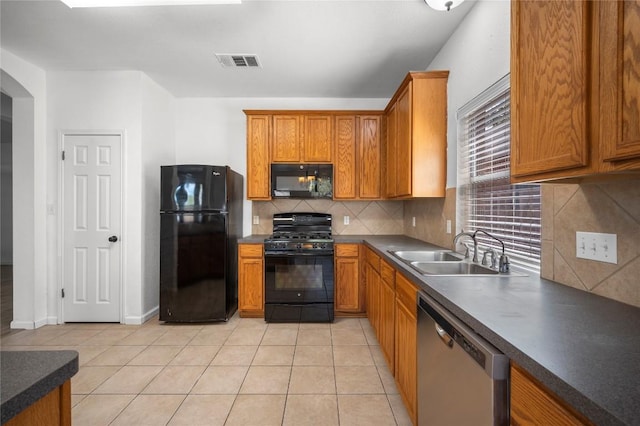 kitchen featuring a sink, tasteful backsplash, visible vents, black appliances, and light tile patterned floors