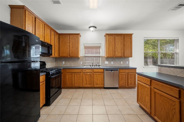 kitchen featuring light tile patterned flooring, sink, decorative backsplash, and black appliances