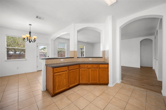 kitchen featuring an inviting chandelier, backsplash, hanging light fixtures, and light tile patterned flooring