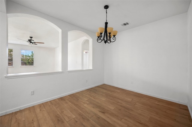 spare room with ceiling fan with notable chandelier and hardwood / wood-style floors