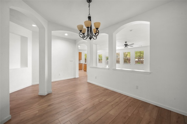 spare room featuring ceiling fan with notable chandelier and light hardwood / wood-style flooring