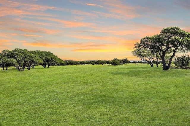 yard at dusk featuring a rural view