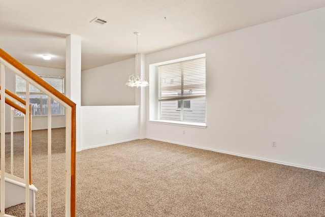 carpeted empty room with an inviting chandelier