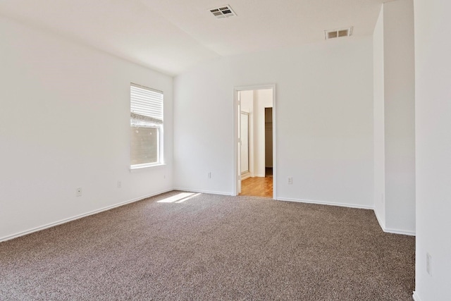 carpeted empty room featuring vaulted ceiling